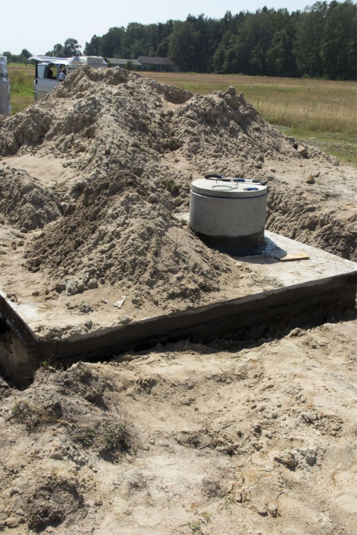 Regard en béton installé sur un terrain excavé dans un environnement résidentiel et rural à Acton Vale