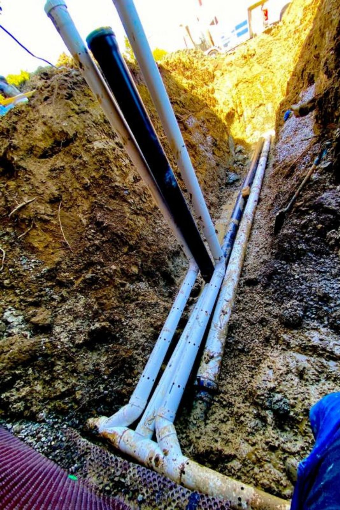 Conduites souterraines apparentes dans une tranchée avec sol excavé et matériaux visibles à Chambly