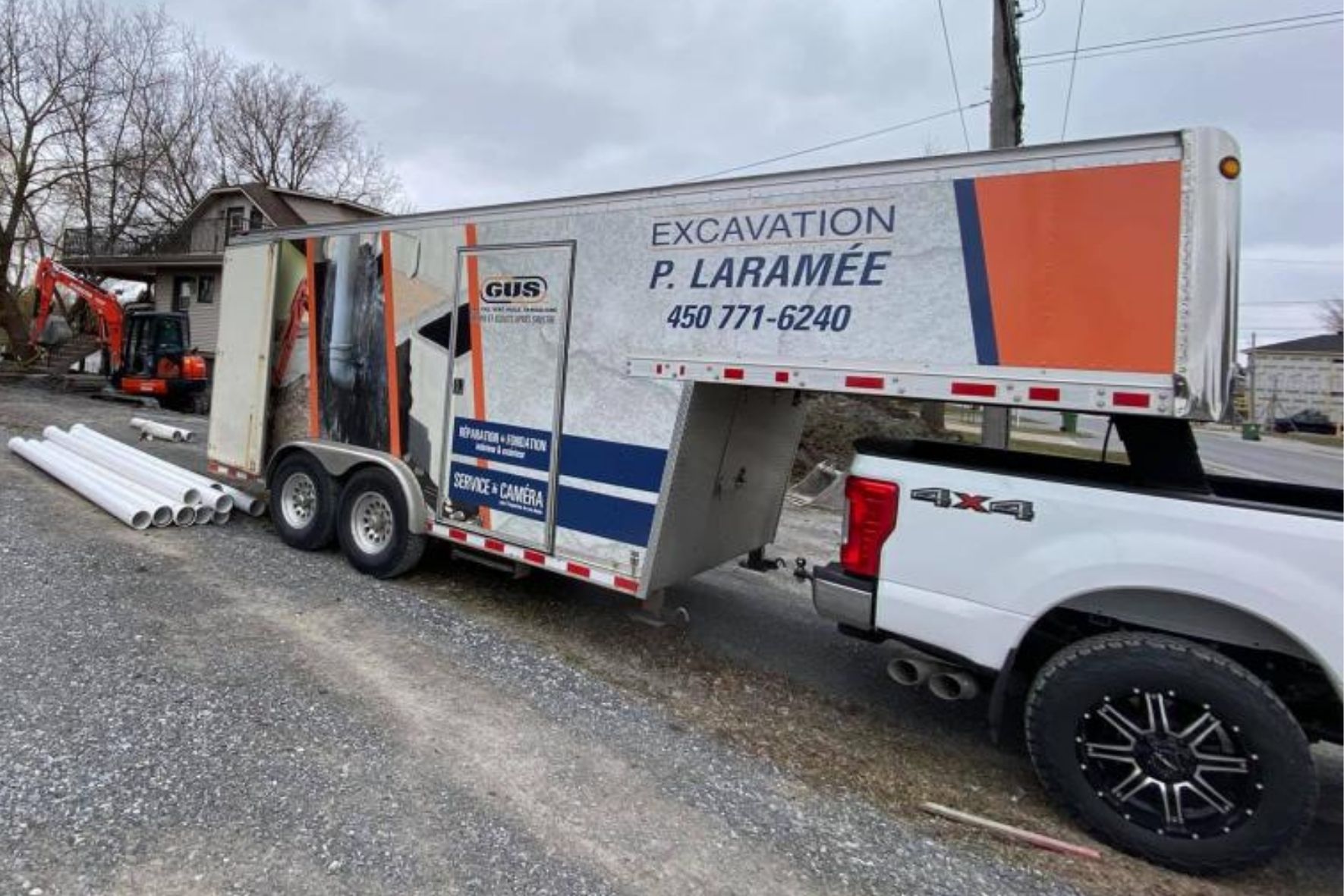 Véhicule utilitaire et remorque stationnés sur un site de travaux résidentiels avec matériaux au sol à Varennes